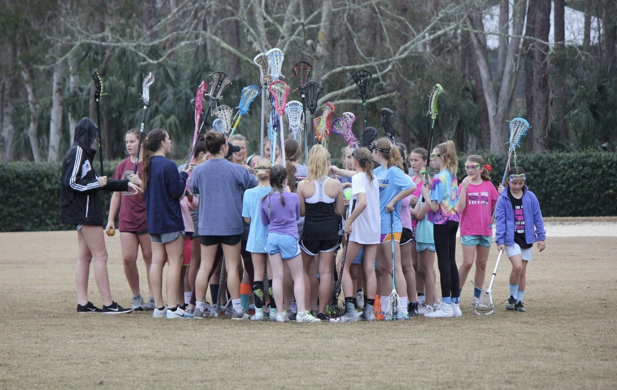 Girls Riptide players raising their sticks together in a team huddle