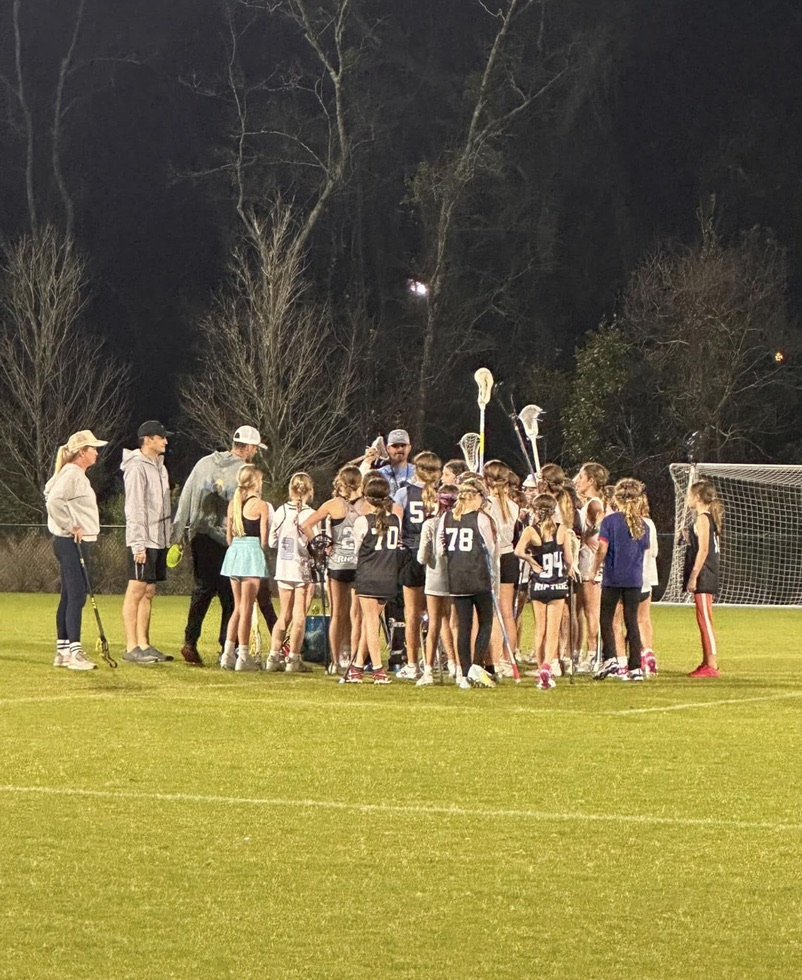 Girls Riptide players gathered with their coaches under the lights
